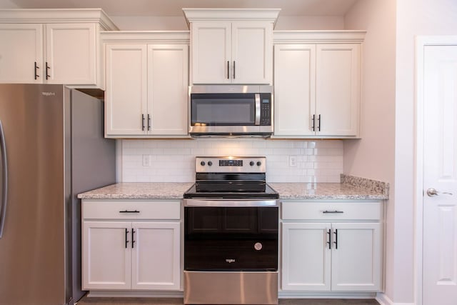 kitchen with appliances with stainless steel finishes, white cabinets, decorative backsplash, and light stone countertops