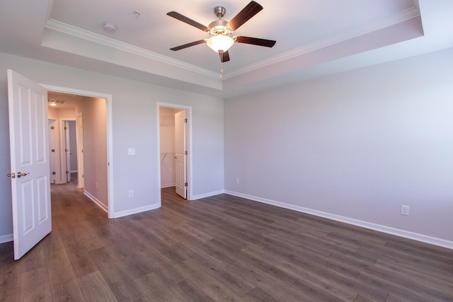 unfurnished bedroom with dark wood-type flooring, a raised ceiling, ornamental molding, and baseboards