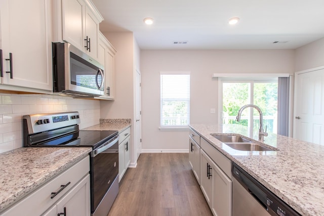 kitchen featuring visible vents, appliances with stainless steel finishes, wood finished floors, a sink, and backsplash