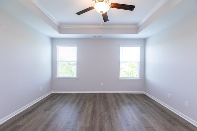 empty room featuring visible vents, a raised ceiling, dark wood finished floors, and crown molding