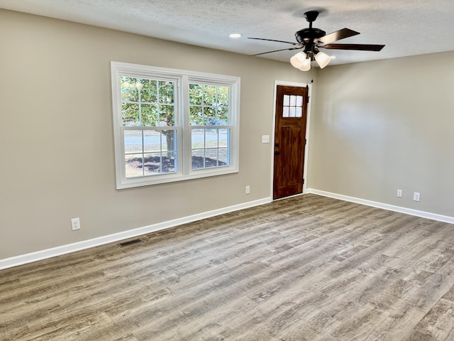 foyer featuring visible vents, ceiling fan, a textured ceiling, wood finished floors, and baseboards