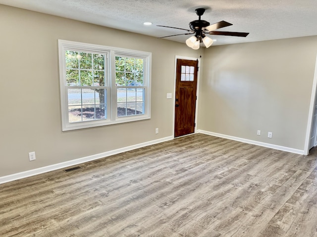 entryway with visible vents, ceiling fan, a textured ceiling, wood finished floors, and baseboards