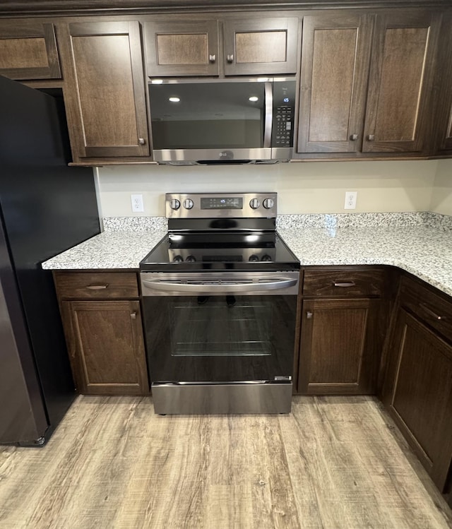 kitchen with stainless steel appliances, light countertops, and dark brown cabinetry