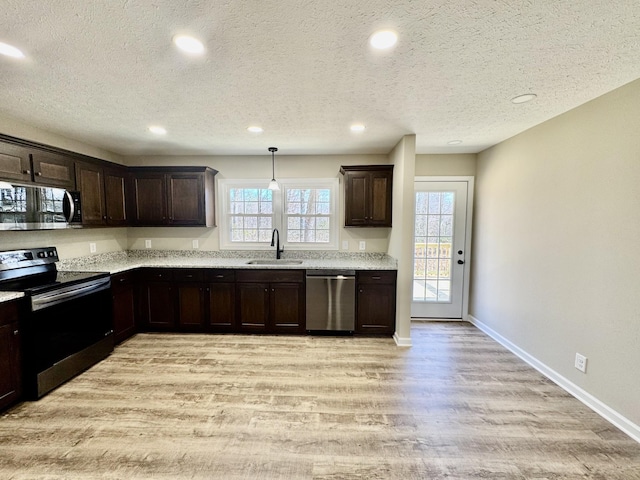 kitchen with dark brown cabinetry, baseboards, appliances with stainless steel finishes, light wood-type flooring, and a sink