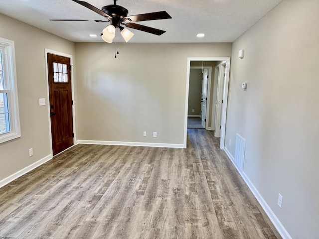 entrance foyer with baseboards, wood finished floors, visible vents, and a healthy amount of sunlight