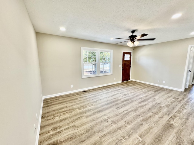 interior space with ceiling fan, a textured ceiling, baseboards, and wood finished floors