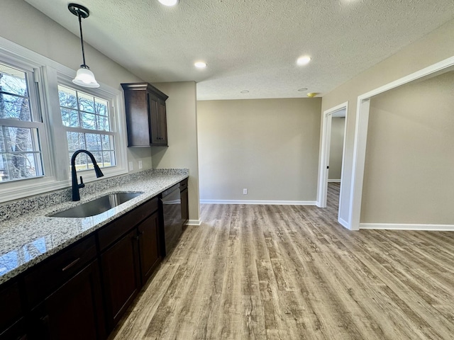 kitchen with light stone counters, a sink, baseboards, light wood-type flooring, and dishwasher