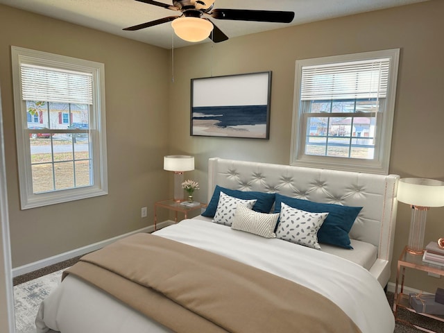 bedroom featuring ceiling fan, multiple windows, and baseboards