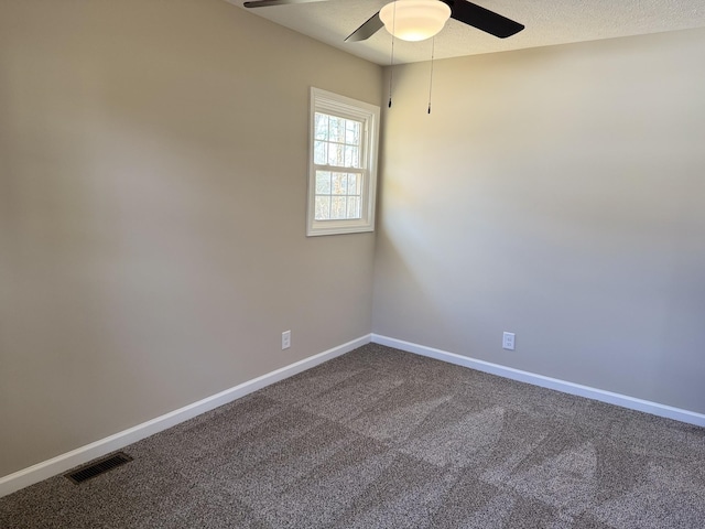 empty room featuring a textured ceiling, a ceiling fan, visible vents, baseboards, and dark colored carpet