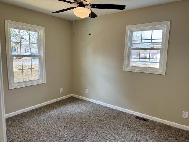 carpeted spare room featuring baseboards, visible vents, and a healthy amount of sunlight