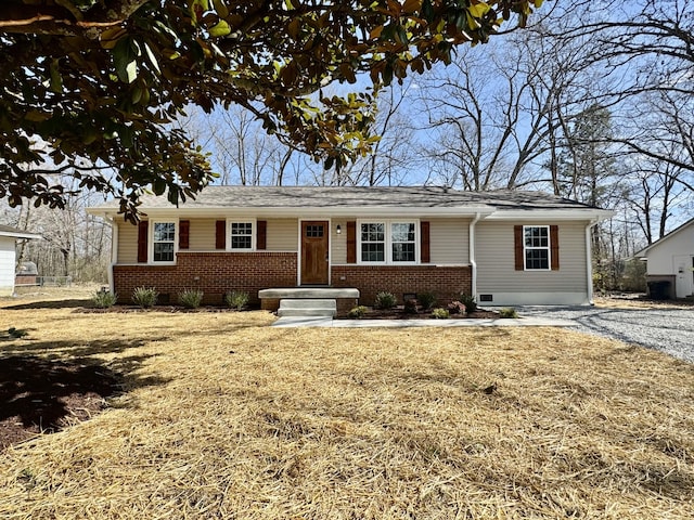 ranch-style home with gravel driveway and brick siding