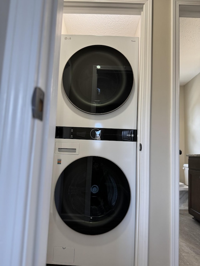 laundry area featuring stacked washer and dryer and a textured ceiling