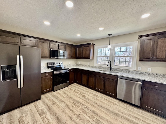 kitchen with stainless steel appliances, recessed lighting, light wood-style floors, a sink, and dark brown cabinets