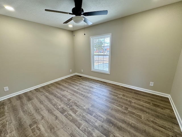 unfurnished room featuring a ceiling fan, dark wood-style flooring, a textured ceiling, and baseboards