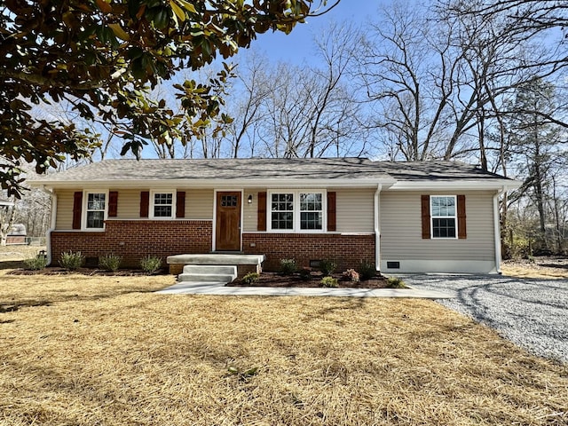 ranch-style home featuring brick siding, crawl space, and gravel driveway