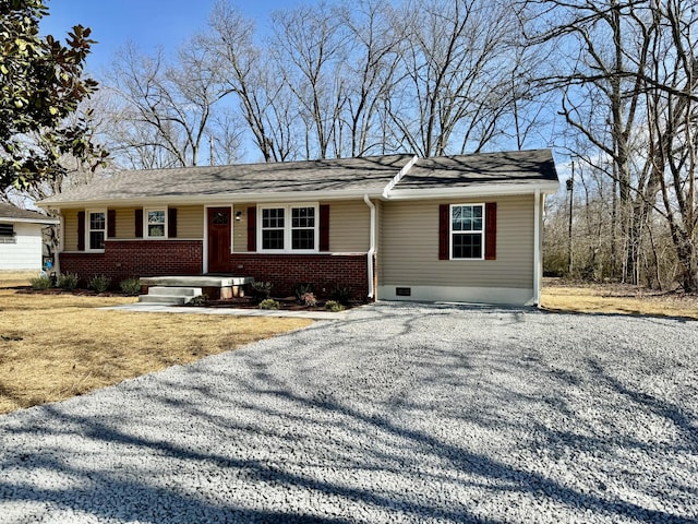 single story home featuring gravel driveway, brick siding, and crawl space