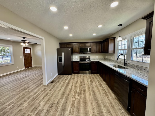 kitchen with dark brown cabinetry, stainless steel appliances, light wood-style floors, a sink, and recessed lighting