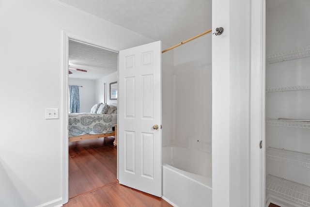 bathroom with a textured ceiling, bathtub / shower combination, and wood finished floors