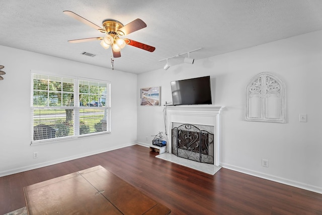 unfurnished living room featuring a textured ceiling, a fireplace, wood finished floors, and visible vents