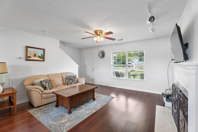 living room featuring a textured ceiling, wood finished floors, visible vents, baseboards, and a high end fireplace