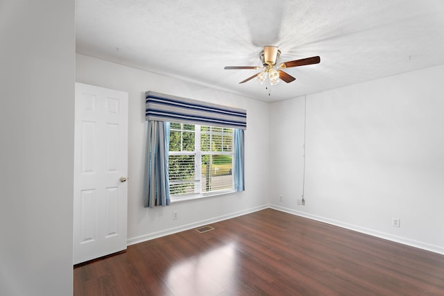 spare room with a textured ceiling, wood finished floors, visible vents, and a ceiling fan