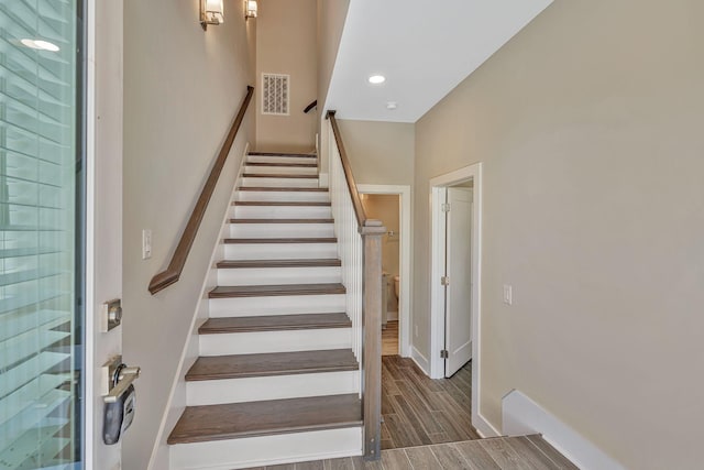 stairs with wood finish floors, recessed lighting, visible vents, and baseboards