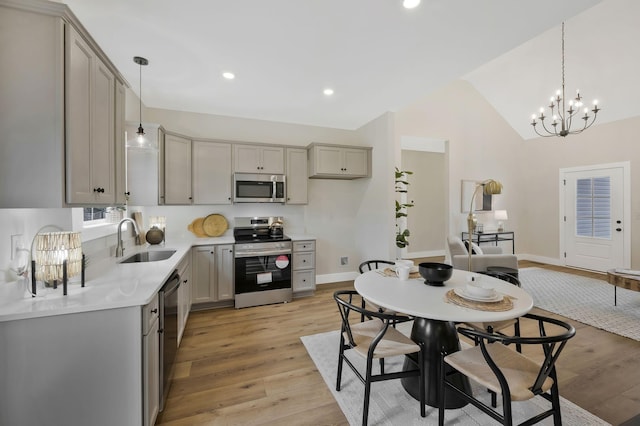 kitchen featuring vaulted ceiling, stainless steel appliances, a sink, and gray cabinetry