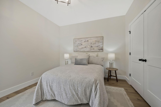 bedroom with light wood-type flooring, a closet, and baseboards