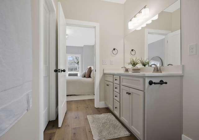 ensuite bathroom featuring double vanity, hardwood / wood-style flooring, ensuite bath, and a sink