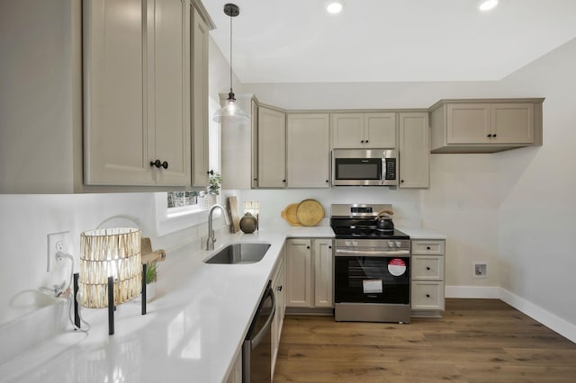 kitchen featuring decorative light fixtures, light countertops, appliances with stainless steel finishes, a sink, and wood finished floors