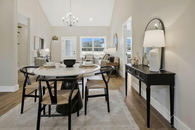 dining space with light wood-type flooring, a notable chandelier, and baseboards