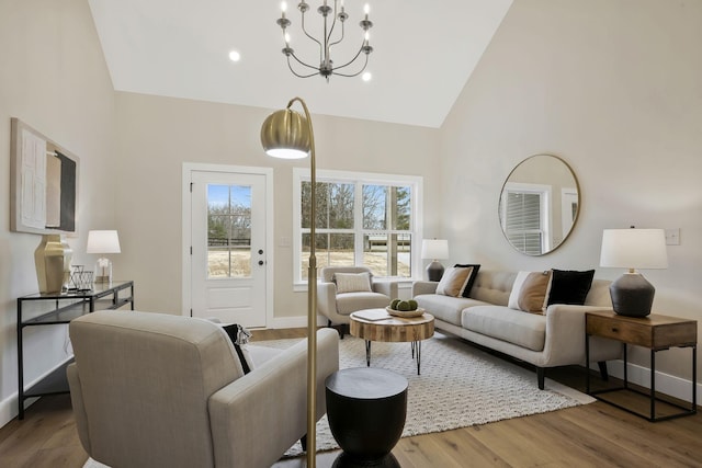 living room with a chandelier, high vaulted ceiling, wood finished floors, and baseboards