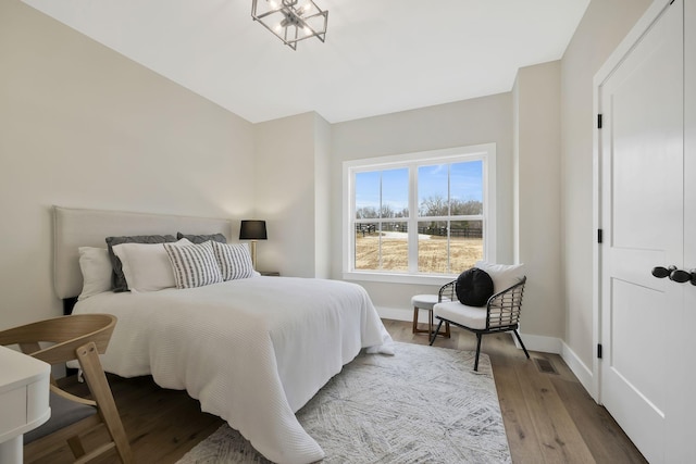 bedroom featuring visible vents, baseboards, and wood finished floors