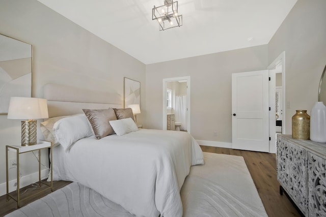 bedroom featuring connected bathroom, baseboards, and wood finished floors