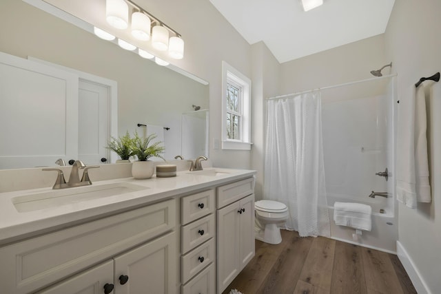 bathroom featuring wood finished floors, shower / bath combo, a sink, and toilet