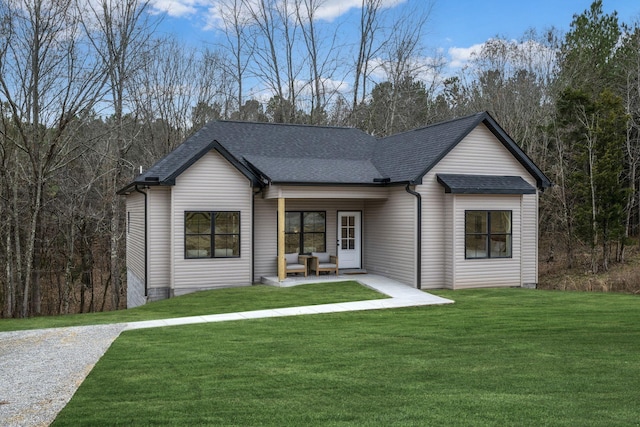 view of front of home featuring a patio area, a shingled roof, and a front lawn