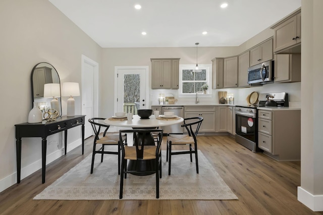 kitchen with recessed lighting, hanging light fixtures, appliances with stainless steel finishes, light wood-style floors, and a sink