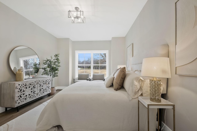 bedroom with an inviting chandelier, baseboards, and wood finished floors