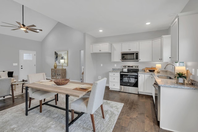 kitchen featuring dark wood finished floors, appliances with stainless steel finishes, white cabinetry, a sink, and light stone countertops