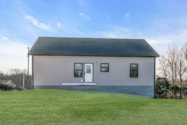 back of property with a yard and a shingled roof