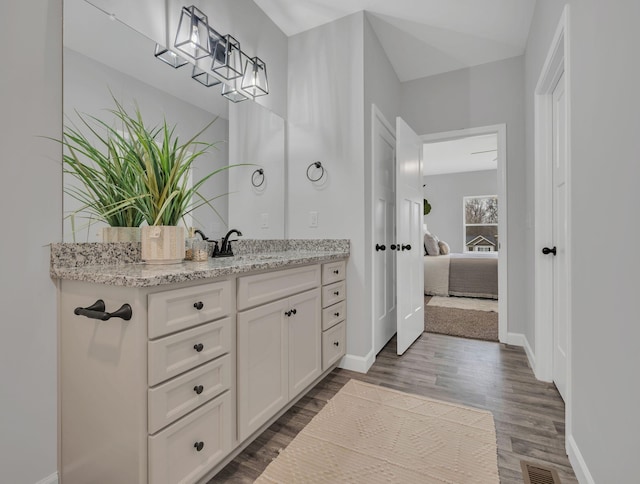 bathroom with wood finished floors, visible vents, vanity, baseboards, and ensuite bath