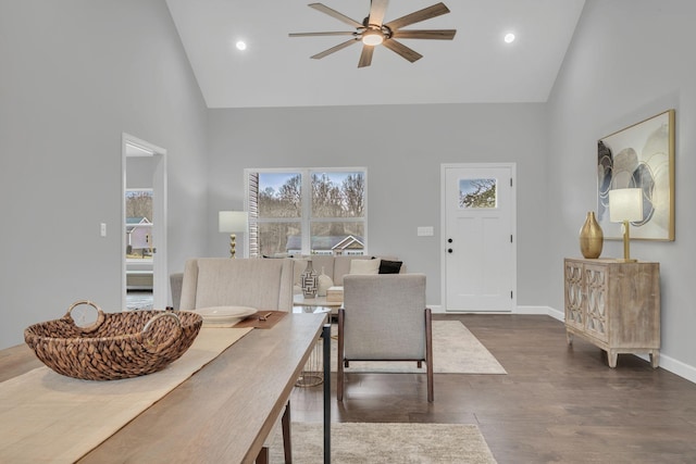 dining room with ceiling fan, high vaulted ceiling, wood finished floors, and baseboards