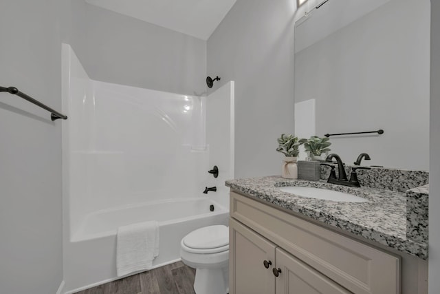 bathroom featuring toilet, vanity, wood finished floors, and shower / bathtub combination