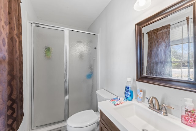 full bathroom featuring a stall shower, vanity, and toilet