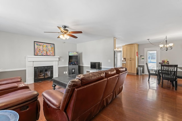 living room with ceiling fan with notable chandelier, wood finished floors, and a glass covered fireplace