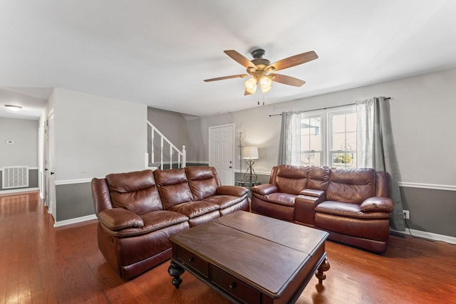 living area featuring ceiling fan, hardwood / wood-style flooring, visible vents, baseboards, and stairs