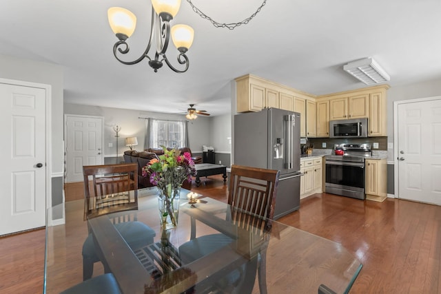 dining room with dark wood-style floors, ceiling fan with notable chandelier, and baseboards