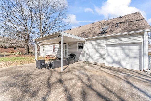 rear view of property featuring driveway, a patio, roof with shingles, and an attached garage