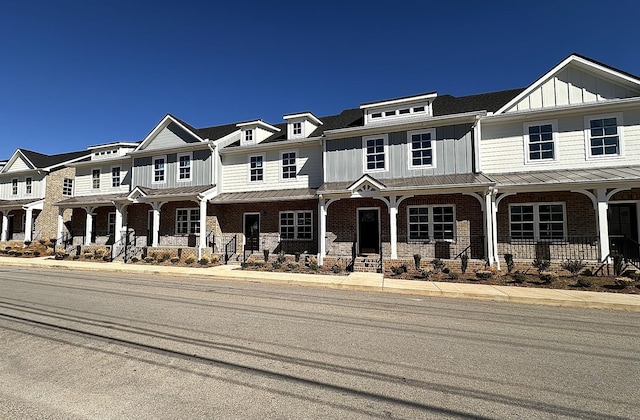 multi unit property with brick siding, a porch, board and batten siding, a standing seam roof, and a residential view