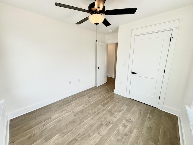 unfurnished bedroom featuring ceiling fan, light wood-type flooring, and baseboards